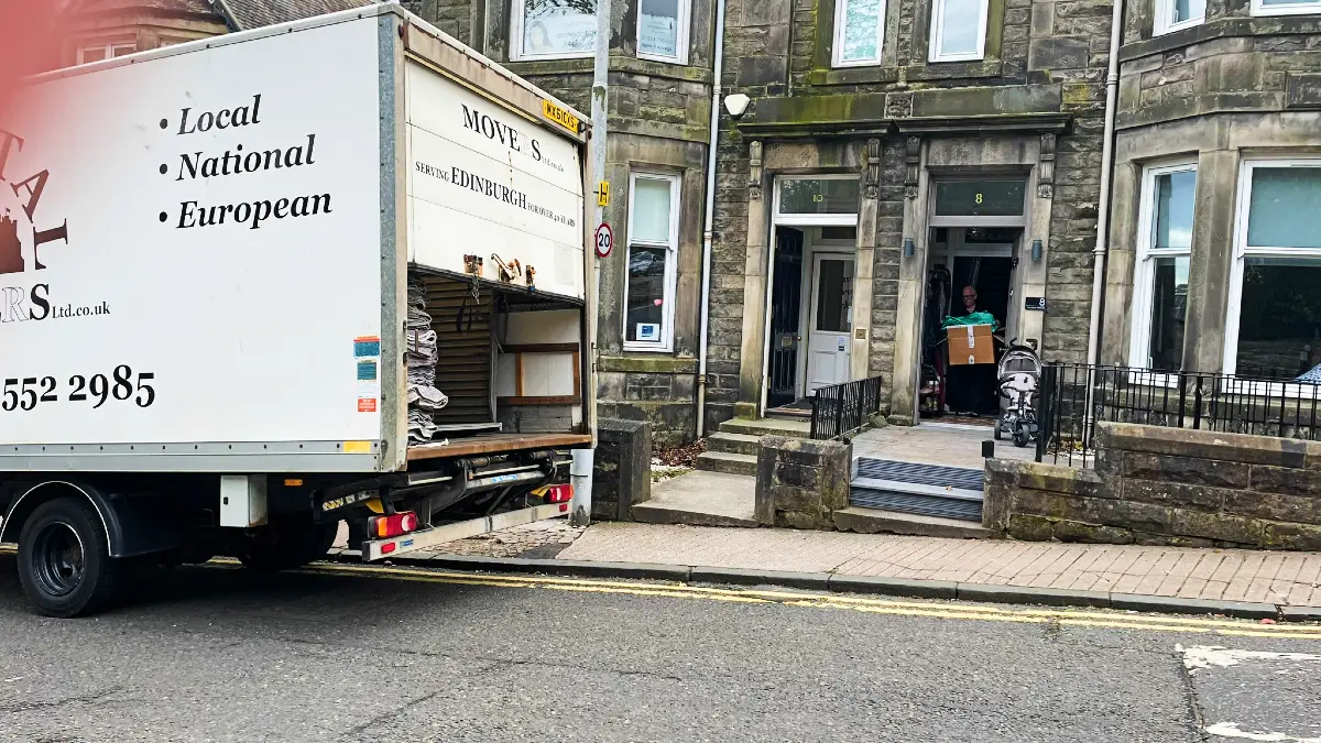 Capital Movers removal van parked on a classic Edinburgh street with period properties, illustrating reliable service in the local community.